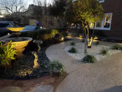 Evening landscape lighting over a fountain and white rock bed